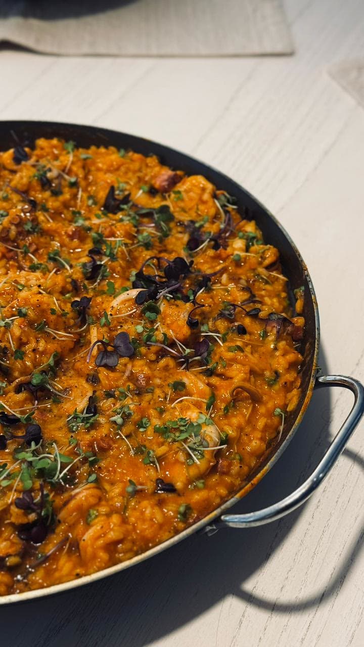 Panela de arroz de frutos do mar com lula, polvo e camarão, finalizada com brotos.